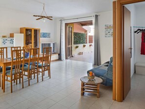 A spacious living area with a dining table, chairs, a sofa, and a small round table with a bowl and a bottle. There is a television and a cabinet with glass doors. - Cosy Holiday Home in Sanremo With Sea Beach Nearby (Alcamo)