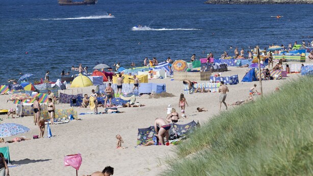 A beach with people sunbathing and swimming, boats in the water, and a lighthouse in the distance. - Holiday Home in a Seaside Village (Darlowo)