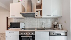 A modern kitchen with white cabinetry, a microwave, an oven, a dishwasher, and a coffee maker.