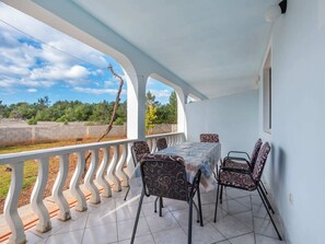A covered outdoor patio with a table and chairs, a view of the landscape, and a white railing. - Homely Apartment in Vir With Balcony (Vir)