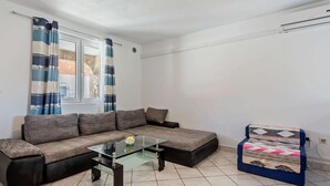 A living room with a sectional sofa, a glass coffee table, and a patterned armchair.