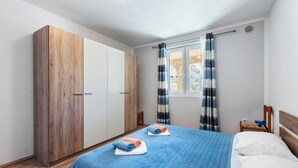 A bedroom with a bed, a wardrobe, a window with curtains, and a view of the outside.
