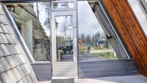 A modern building with a glass door entrance, a sloped roof, and a wooden exterior.
