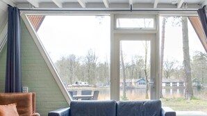 A room with a large window, a brown leather sofa, and a black leather couch.
