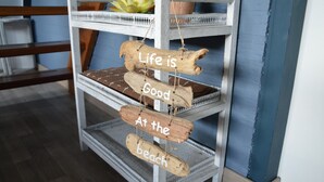 A multi-tiered wooden shelf with three signs saying "Life is Good at the beach."