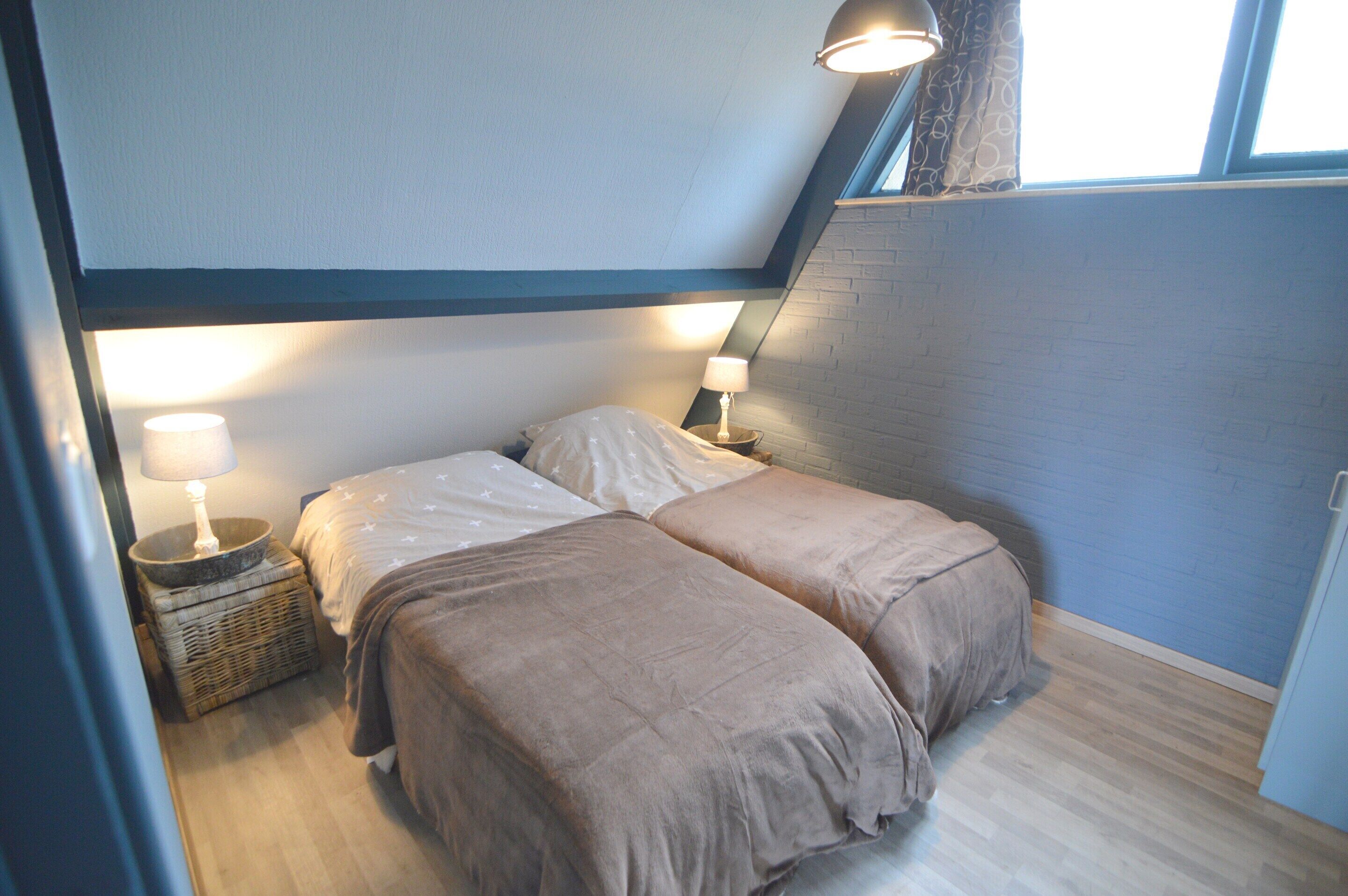 Un dormitorio con dos camas, una ventana y una lámpara sobre una mesita de noche.