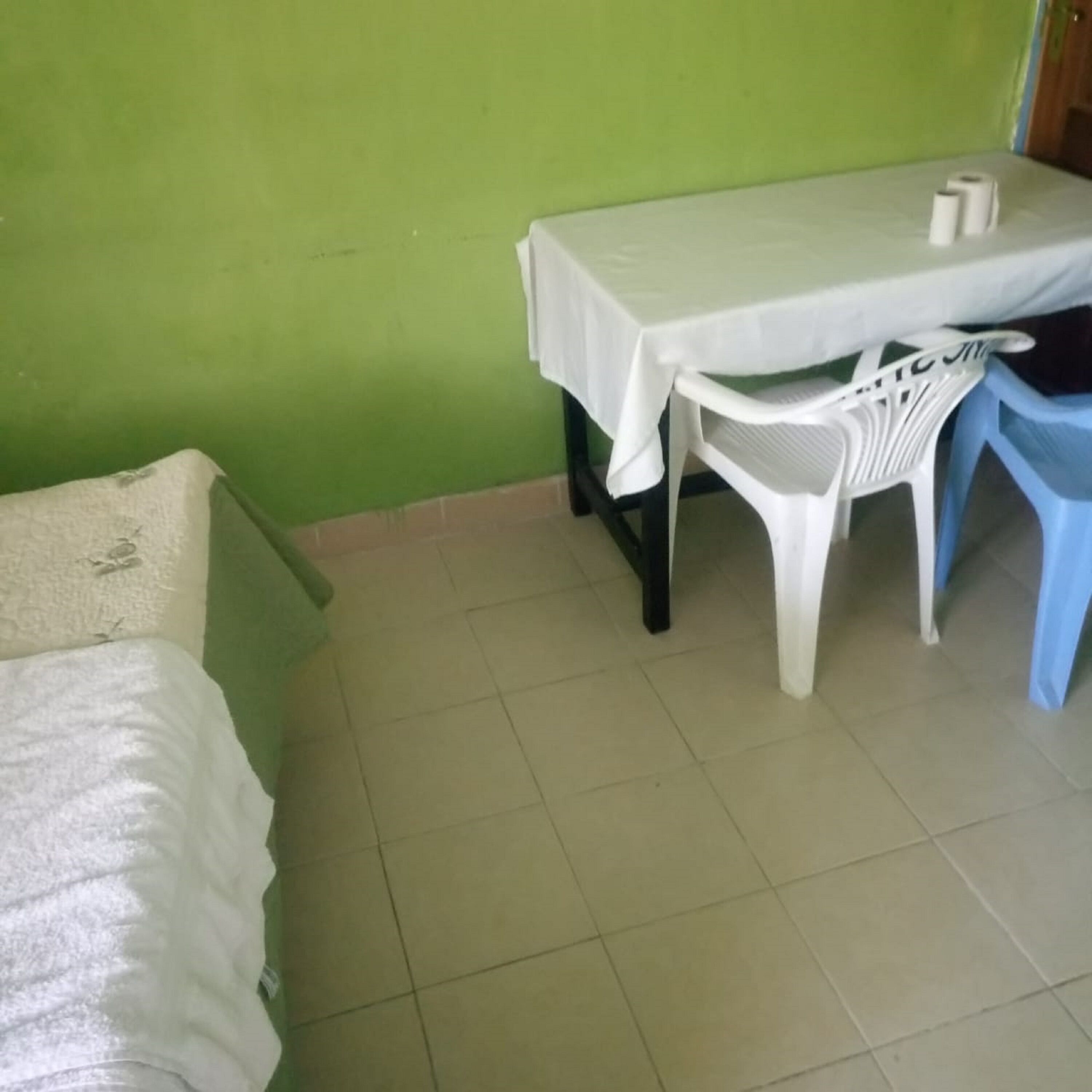 A room with a single bed, a table with chairs, and a green wall.