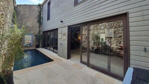 Una casa moderna con fachada de piedra, piscina y grandes puertas correderas de vidrio.