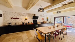 Una cocina rústica con pared de piedra, una mesa de comedor de madera y sillas coloridas.