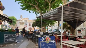 Un café a la calle con mesas al aire libre, un cartel de menú y un letrero que dice Martin's Restaurant.