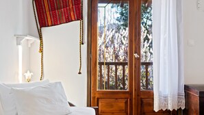 A hotel room with a bed, a wooden door, and a view of trees through the window. - Snug Apartment in Agios Nikolaos With Garden (Sithonia)