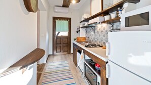 A narrow kitchen with wooden cabinets, a white refrigerator, and a striped rug. - Snug Apartment in Agios Nikolaos With Garden (Sithonia)