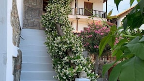 A staircase with white walls and a stone base, leading to a balcony with a tiled roof. - Snug Apartment in Agios Nikolaos With Garden (Sithonia)