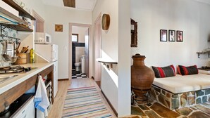 A kitchen with a wooden countertop, a stove, and a microwave. There is a hallway leading to a bathroom. - Snug Apartment in Agios Nikolaos With Garden (Sithonia)