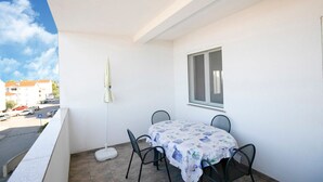 A balcony with a table and chairs, a window, and a view of the street. - Tasteful Apartment in Zadar With Balcony (Zadar)