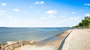 A beach with clear water, a concrete walkway, and trees along the shore. - Tasteful Apartment in Zadar With Balcony (Zadar)