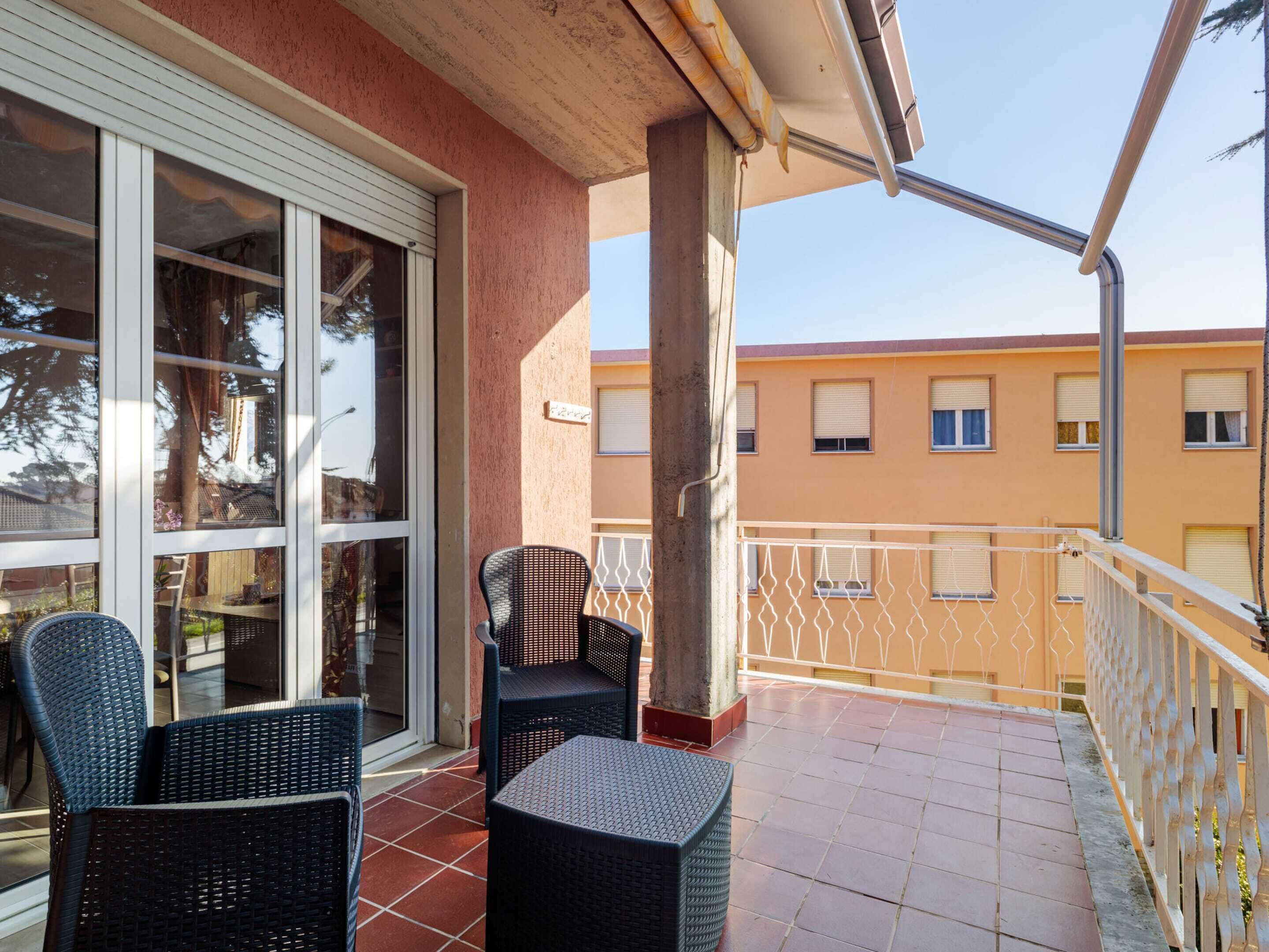 A balcony with wicker furniture, a sliding glass door, and a view of a yellow building in the background.