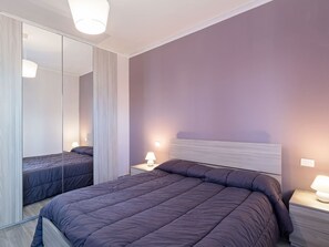 A modern bedroom with a large bed, bedside tables with lamps, a mirror, and a light-colored headboard.