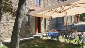 Un edificio de piedra con un patio que tiene asientos al aire libre y una mesa con mantel.