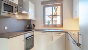 A modern kitchen with white cabinets, a built-in oven, a microwave, and a window with a view of the outside. - Cozy Chalet in Weisspriach With Terrace (Weisspriach)