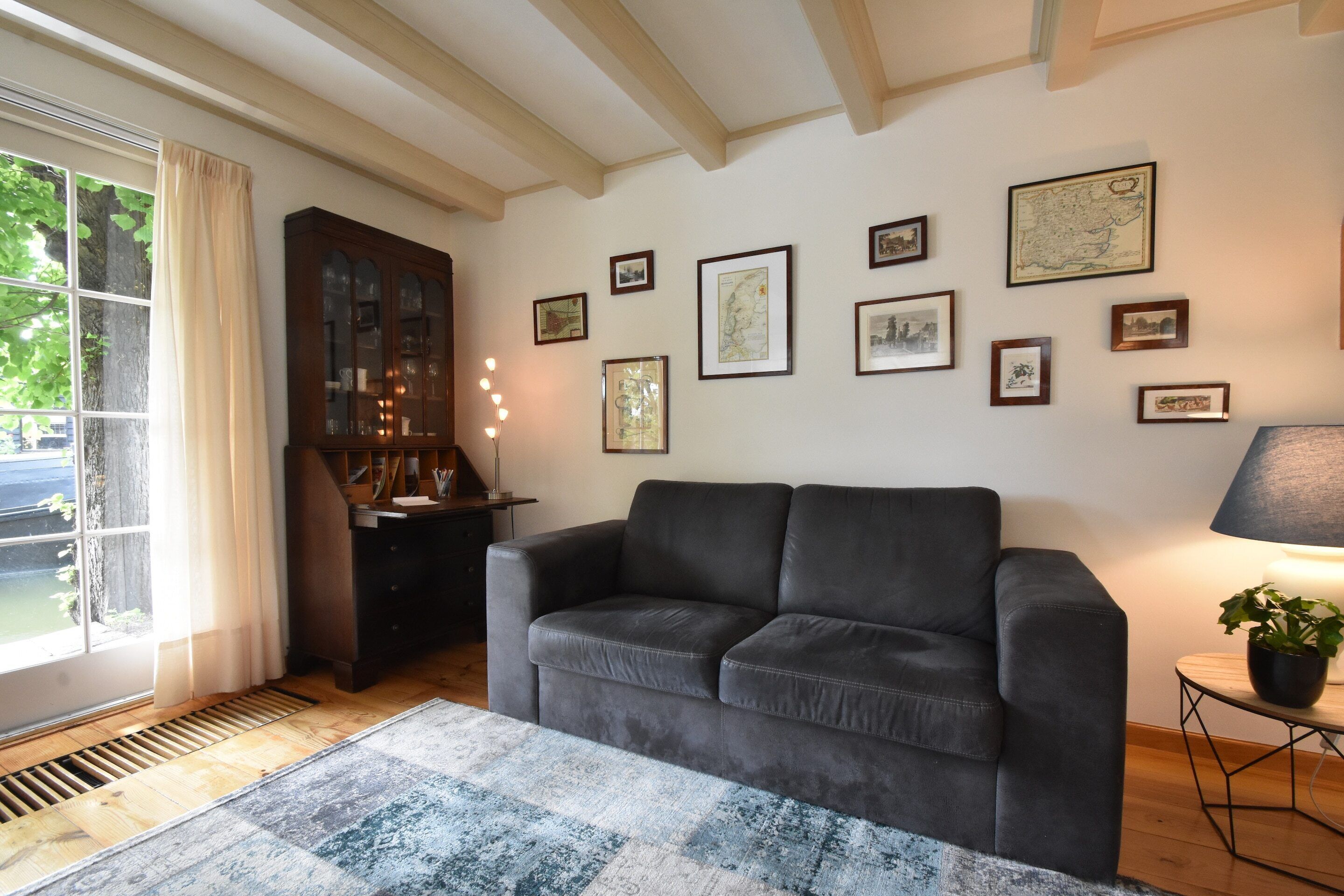 A living room with a dark leather sofa, a wooden cabinet, and a rug.