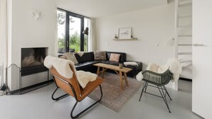 Un salon moderne avec une cheminée, un canapé, une table basse et un fauteuil.