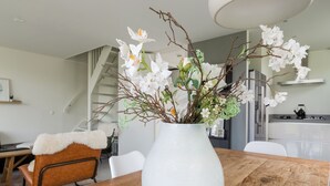 Une cuisine moderne avec des armoires blanches, une hotte de cuisinière en acier inoxydable et une bouilloire noire posée sur la plaque de cuisson.