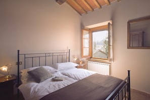 A bedroom with a bed, bedside lamps, a window, and a radiator. - Farmhouse in Arezzo, Elba (Arezzo)