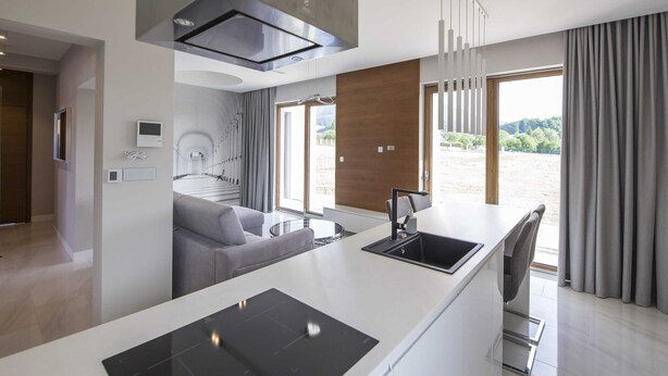 Cozinha moderna com ilha central, eletrodomésticos embutidos e uma ampla janela com vista para o exterior.