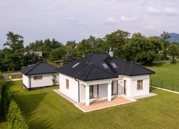 Stunning two-story house with a symmetrical design, featuring a central section and two smaller wings.