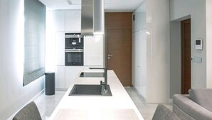 Uma cozinha moderna com ilha central, forno embutido e eletrodomésticos de aço inoxidável.