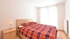 A bedroom with a bed, a nightstand, a lamp, and a window with blinds. - Tasteful Apartment Near the Centre and Beach of Bredene (Bredene)