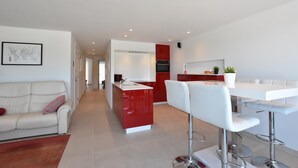 A modern kitchen with a central island, white bar stools, and a red accent wall. - Tasteful Apartment Near the Centre and Beach of Bredene (Bredene)