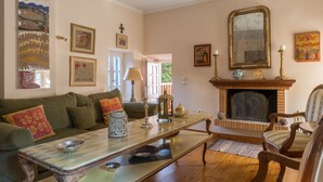 Ein gemütliches Wohnzimmer mit Kamin, einem grünen Sofa, einem Couchtisch und verschiedenen Dekorationselementen.