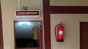 Una zona de recepción con un cartel, un extintor y suelo de baldosas.