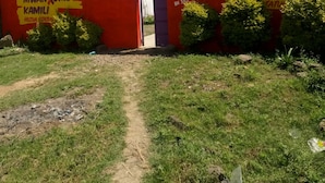 Un edificio rojo con un letrero que dice 'Mwanume Kamili' y 'My Choice Guest House'.