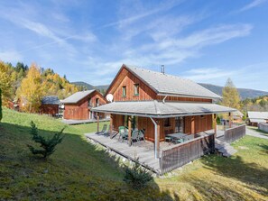 A wooden cabin with a covered patio, surrounded by a grassy area and trees. - Quaint Family Chalet in Stadl an der Mur near Ski Area (Stadl-Predlitz)