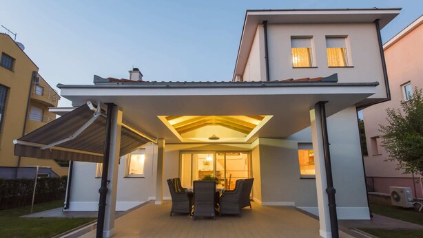 A modern house with a covered patio area featuring a dining set and a glass door leading to the interior. - Seaside Villa in Zadar With Swimming Pool (Zadar)
