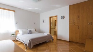 A modern bedroom with a bed, wooden wardrobe, and a small table. - Seaside Villa in Zadar With Swimming Pool (Zadar)