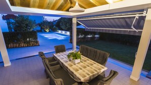An outdoor patio with a table and chairs, a pool, and a covered area with a view of the backyard. - Seaside Villa in Zadar With Swimming Pool (Zadar)