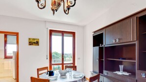 A dining area with a round table, chairs, and a view through a large window.