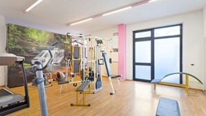 A gym with exercise equipment, a mural, and a bench.