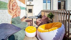 Un patio con mobiliario exterior, un mural y una valla de madera.