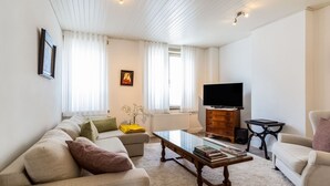 Una sala de estar con sofá, mesa de centro, televisor y una mesita auxiliar.
