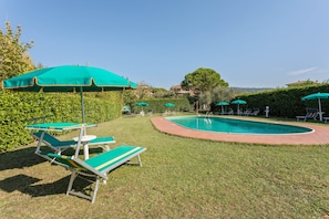 A pool area with green and white lounge chairs and umbrellas, surrounded by well-maintained grass and hedges. - Apartment in Tuoro Near Lago Trasimeno (Tuoro sul Trasimeno)