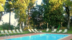 A rectangular swimming pool with a tiled edge, surrounded by a brick deck.