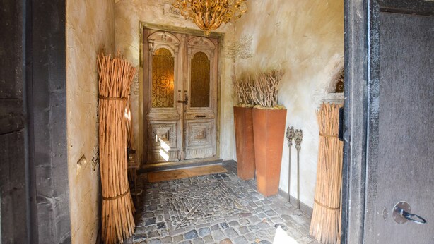 An entrance with a stone floor, a wooden door, and a chandelier. - Posh Holiday Home in Alphen with Hot Tub (Alphen)