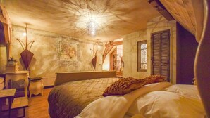 A bedroom with a bed, a desk, and a chair. There is a window with shutters and a chandelier. - Posh Holiday Home in Alphen with Hot Tub (Alphen)