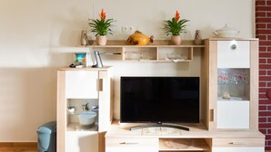 A modern living room with a flat-screen TV, wooden furniture, a small fish tank, and decorative plants. - Delightful Apartment in Vir With Garden (Vir)