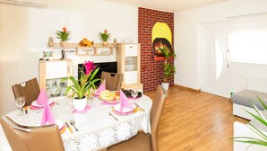 A dining area with a table set for four, surrounded by chairs. There is a brick wall with a decorative element and a potted plant. - Delightful Apartment in Vir With Garden (Vir)